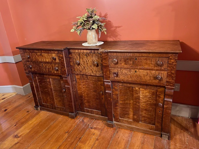 a wooden sideboard in a room with a hardwood floor